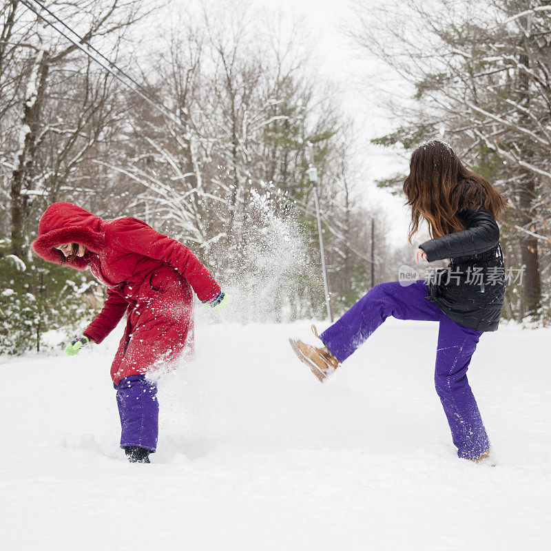 两个女孩，姐妹，在冬天的森林里玩雪