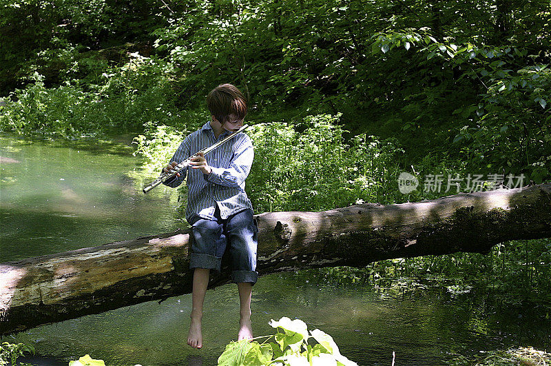 小男孩在河上的木桩上吹笛子