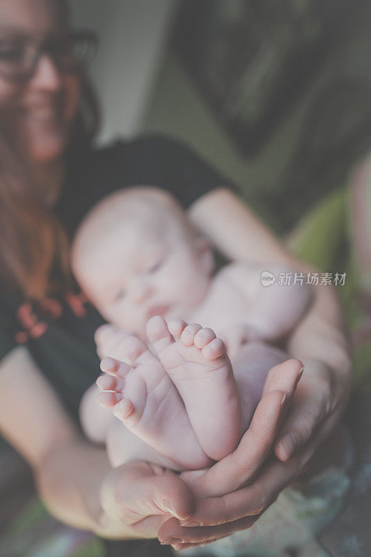 爱的妈妈抱着刚出生的宝宝露出脚