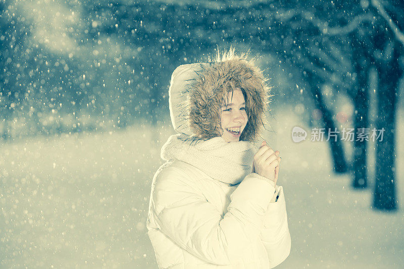 雪下穿着白色夹克的漂亮少女