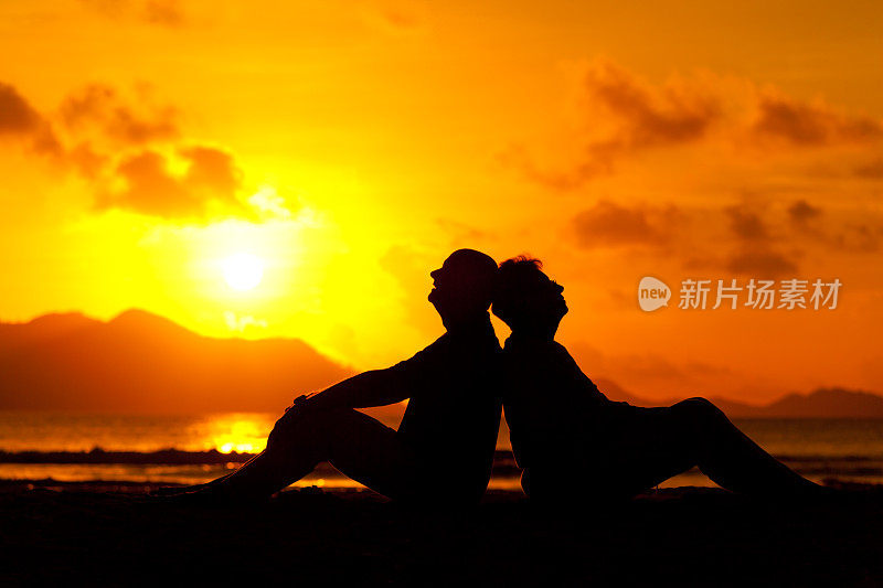 日落时分，一对夫妇坐在海滩上