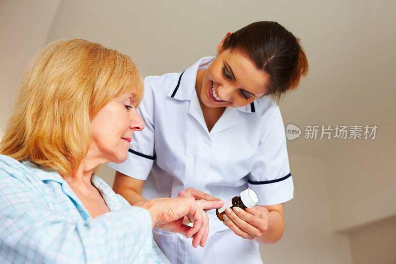 女护士向一位老年病人解释药物治疗