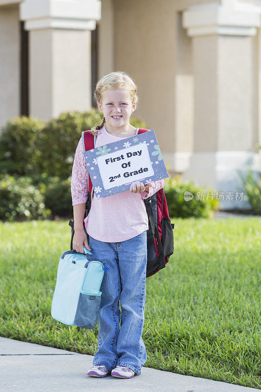 小女孩带着午餐盒和书包回到学校