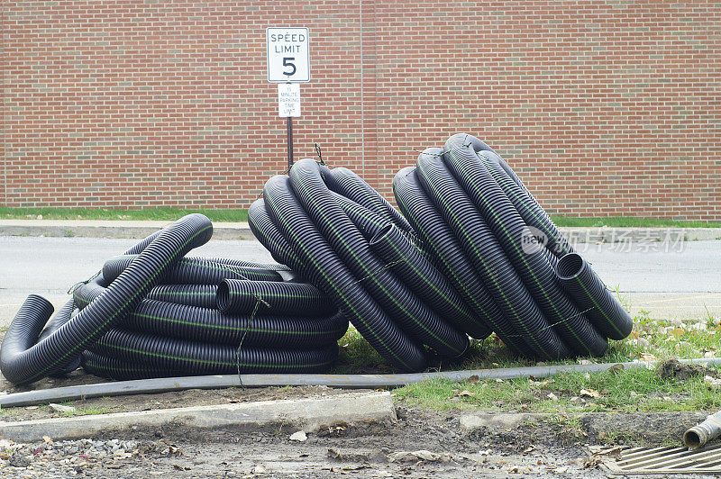 黑色塑料管卷曲着躺在停车场里