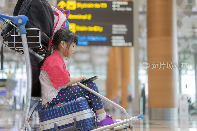一个女孩坐在机场的行李箱上
