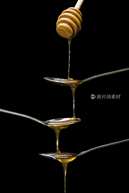 蜂蜜从木制的蜂蜜勺滴进银勺