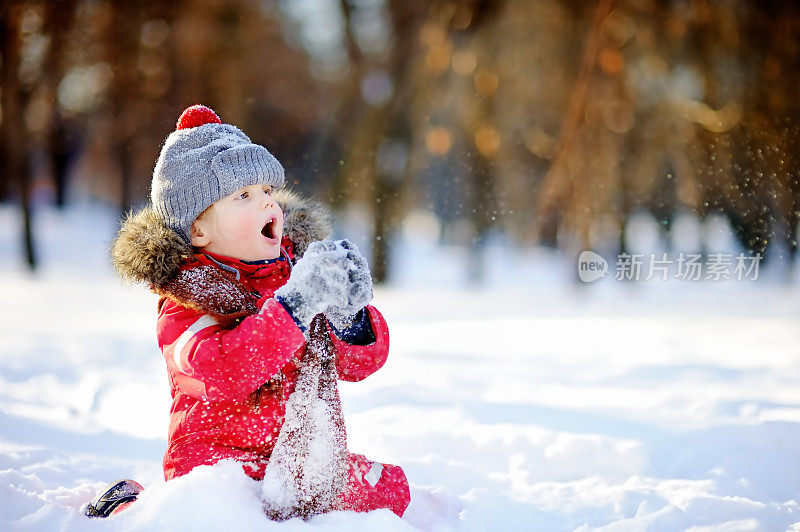 小男孩穿着红色的冬装和雪玩