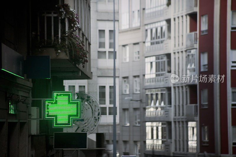 药店的标志在街上，高楼林立，绿十字。