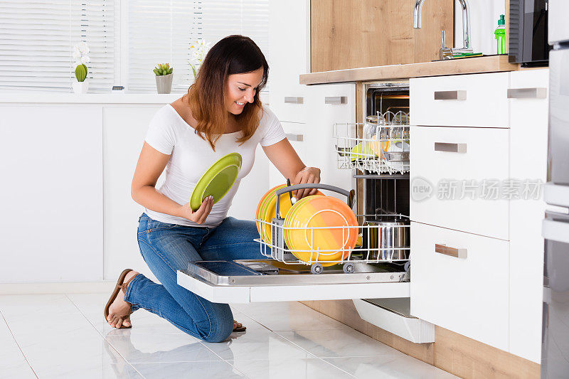 在洗碗机里整理盘子的女人