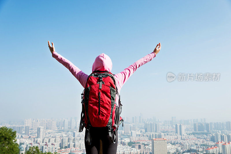 女背包客在山顶张开双臂