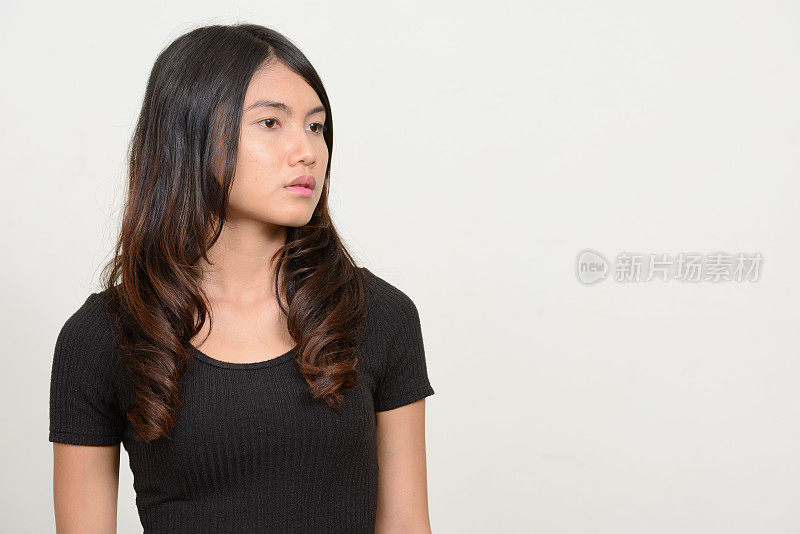 工作室拍摄的年轻美丽的亚洲女子穿着黑衬衫，以白色为背景