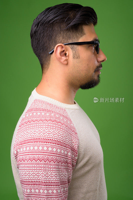 年轻的留胡子的伊朗男子穿着休闲衣服，背景是绿色