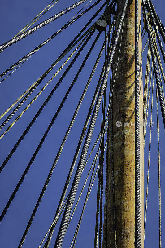 蓝色的天空映衬着古老的船桅和绳索。