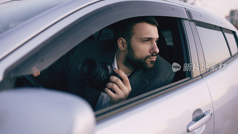 年轻私家侦探坐在车里，用单反相机拍照