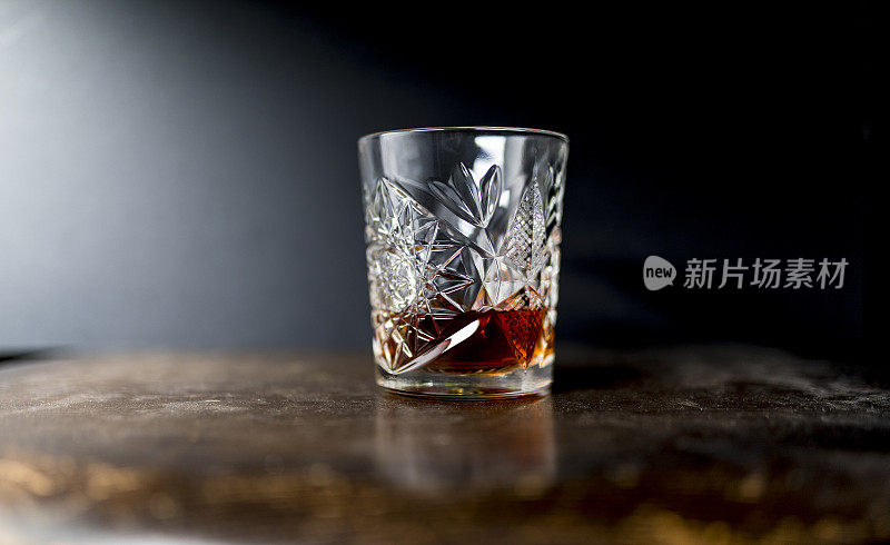 威士忌(或波旁威士忌)在一个豪华的重切水晶玻璃玻璃杯中，木质桌子上的黑色背景