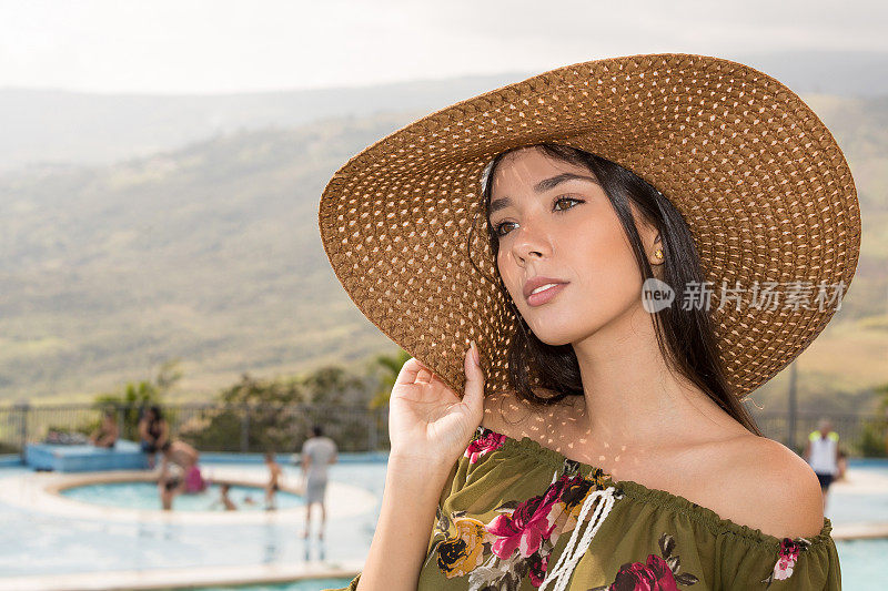 年轻的女士肖像户外拿着一顶大帽子看远