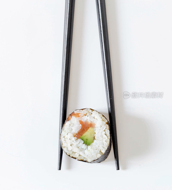 寿司卷在黑色的筷子孤立在白色的背景。日本料理
