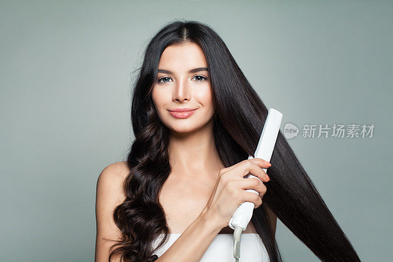 有吸引力的女人与卷发和长直发使用直发器。头发问题和护发概念