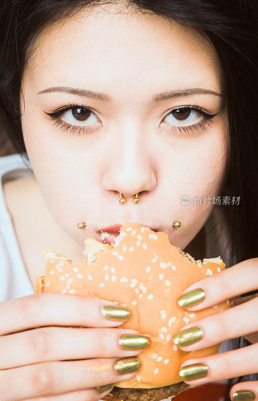 年轻的亚洲女人在吃汉堡包
