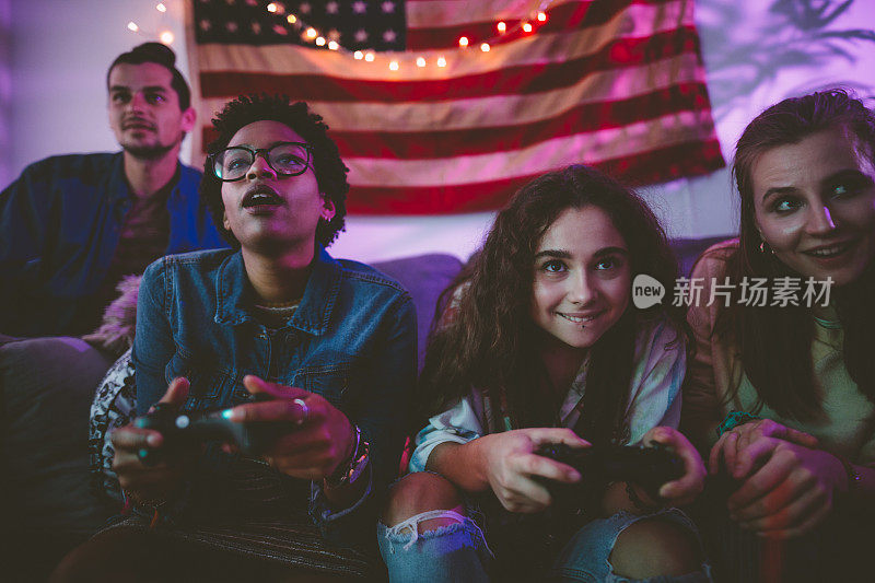 快乐的多民族青少年朋友们用控制器玩电子游戏