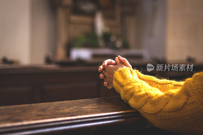 基督教妇女在教堂里双手交叉祈祷。相信耶稣基督