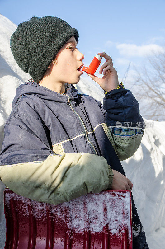 小男孩在铲雪后使用哮喘泵