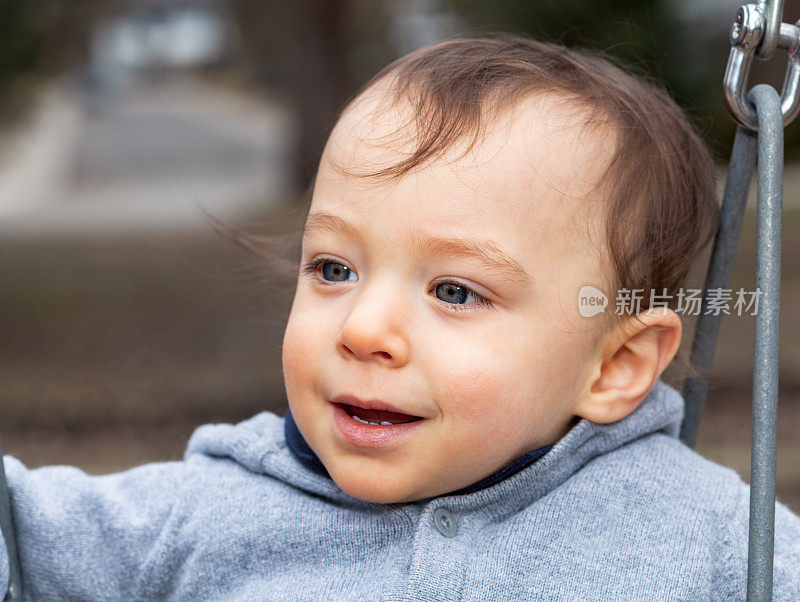 18个月大的蓝眼睛男婴在室外看着别处
