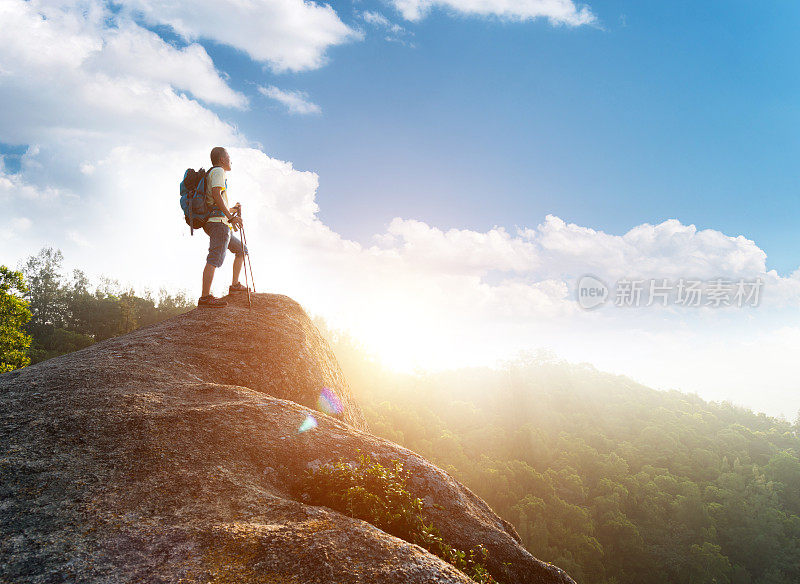 男性徒步旅行者站在山顶的一块岩石上