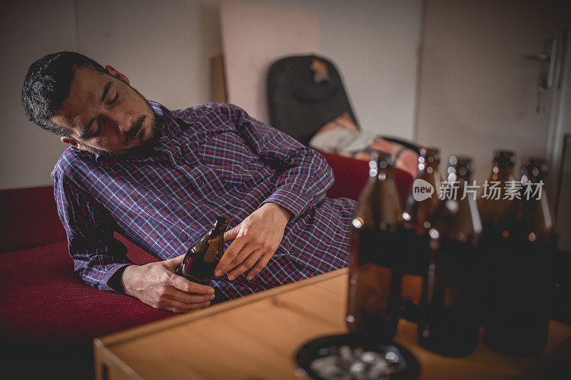 年轻悲伤的醉酒男子喝啤酒和酒精感到浪费，孤独和绝望的痛苦和情绪压力。人与酗酒、上瘾和男人抑郁的概念。