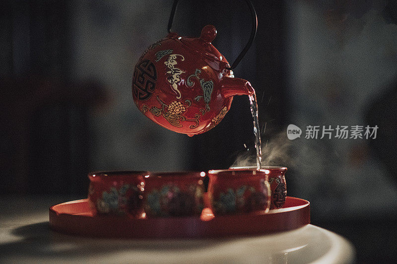 在中国婚礼茶道上，将热茶从传统的茶壶倒入托盘上的茶杯中