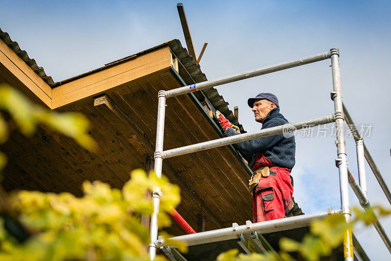 脚手架上的工人正在翻新木屋顶结构