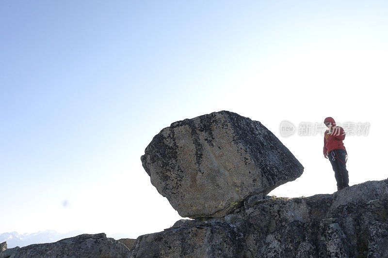 登山者拿着相机站在悬崖顶上