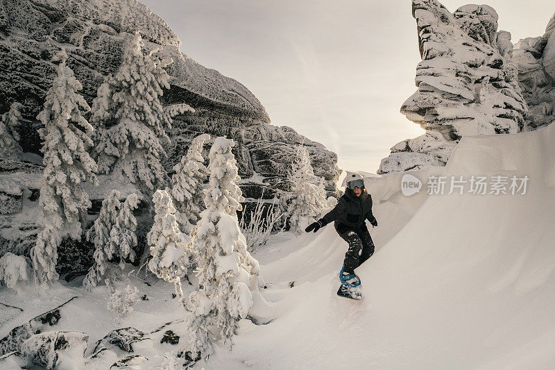 滑雪板女骑在雪上在陡峭的斜坡上看起来像一个海浪冲浪，冬天的一天，白雪覆盖的树木，美丽的悬崖，免费在滑雪胜地