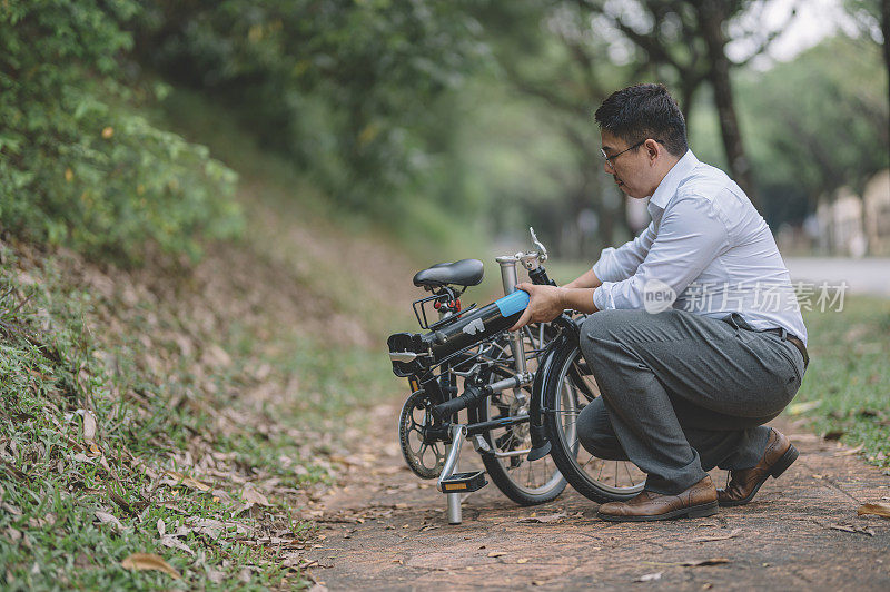一名亚洲华裔白领管理人员，用折叠自行车展开，设置