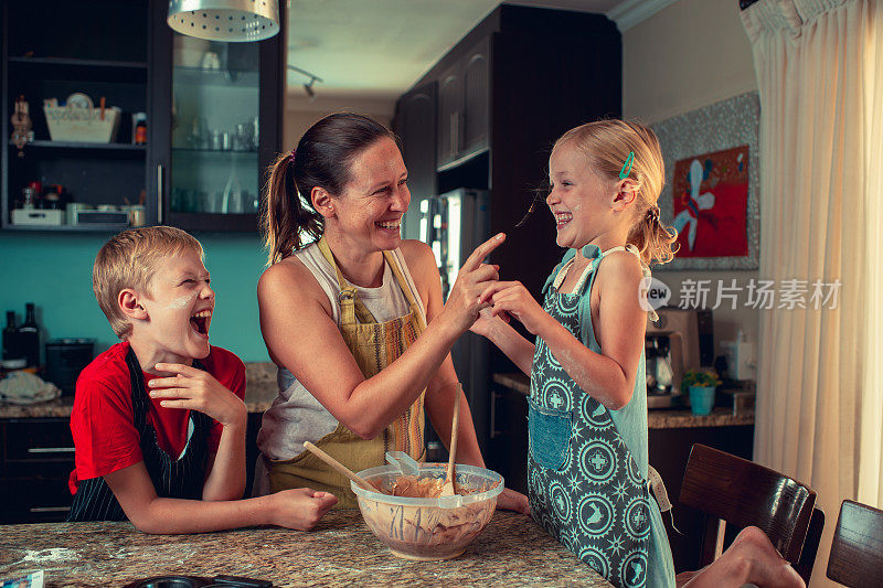 妈妈和孩子们在厨房烤面包，摸他们的鼻子玩得很开心