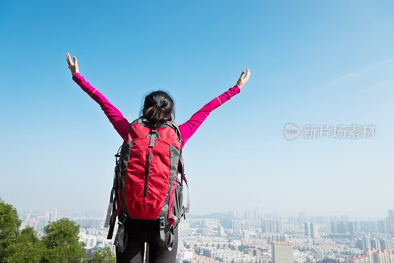 女背包客在山顶张开双臂