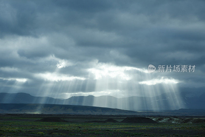 冰岛的山和山脉景观。阳光冲破乌云密布的天空