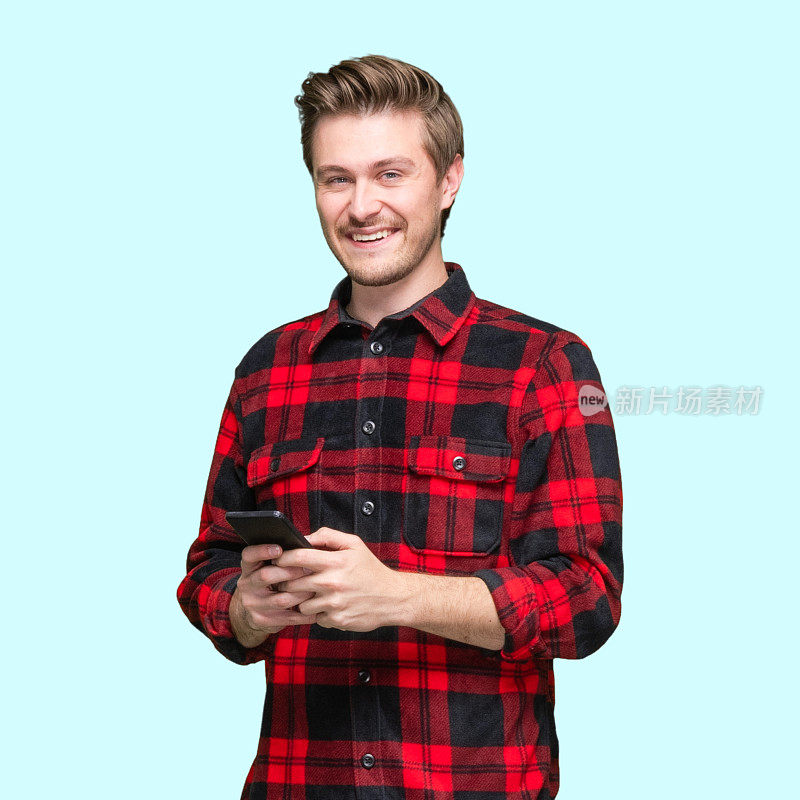 白人男性穿着衬衫站在蓝色背景前使用智能手机