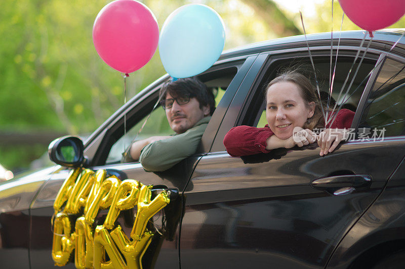 家人在传染病流行期间从他们的车祝朋友或亲戚生日快乐。他们保持社交距离，并戴上防护口罩
