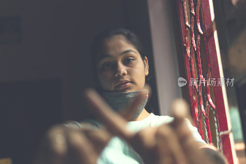 这个悲伤的女孩正在保护自己，戴着口罩，在家里自我隔离。