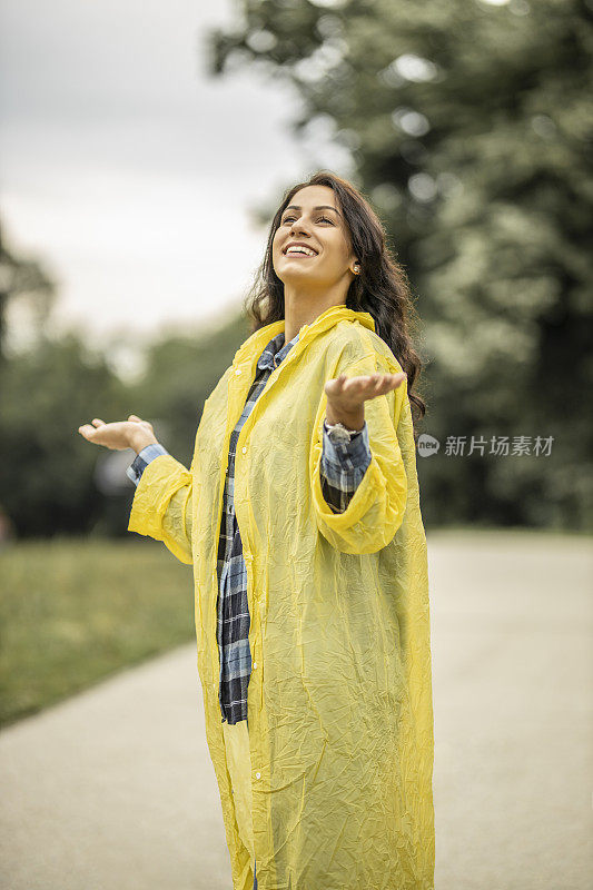 穿着黄色雨衣的年轻女子在雨天享受