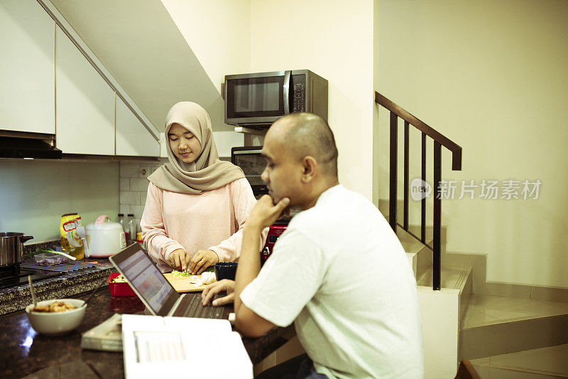 亚洲穆斯林妇女做饭时，丈夫在家工作