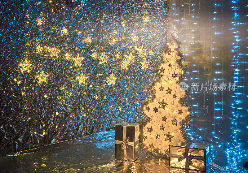 明亮的圣诞树和礼物。银色墙上闪烁的星星