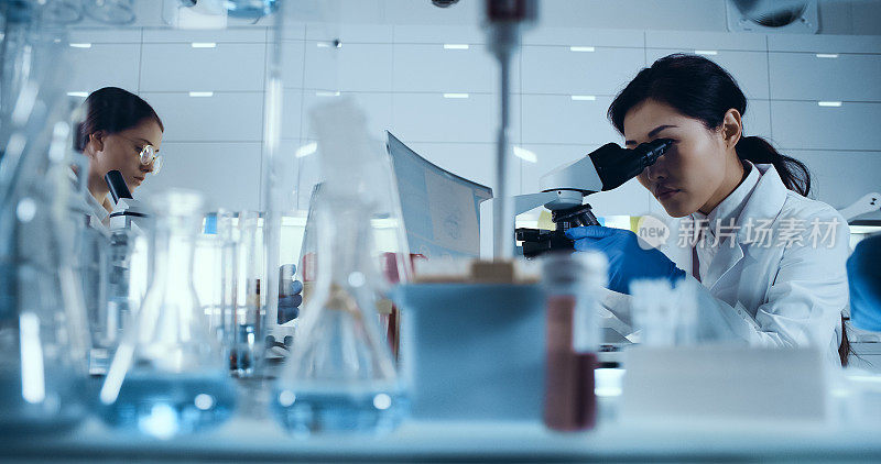 基因研究实验室。亚洲女医生使用显微镜，研究伙伴背景