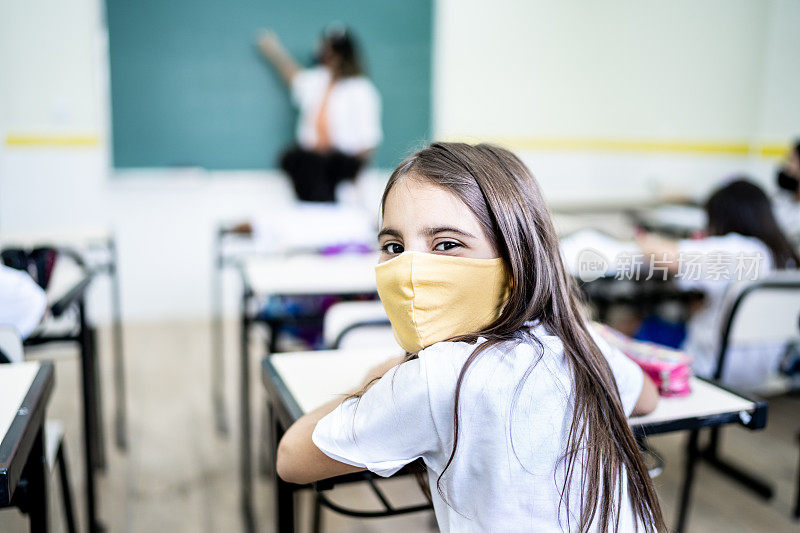 一个女学生在教室里用面具学习的肖像