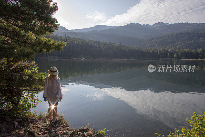 成熟的女人带着书和水瓶，停在湖边