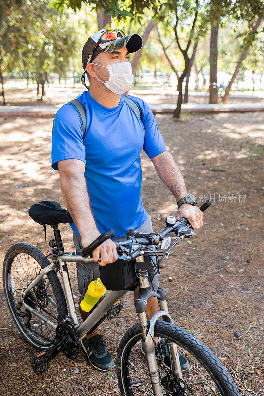 成年男子戴口罩以保持健康，并在周日骑自行车