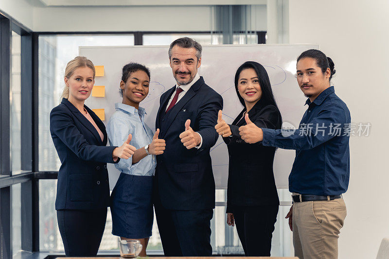 成功开朗的商务人士群的多种族商务团队与拇指和微笑摆姿势