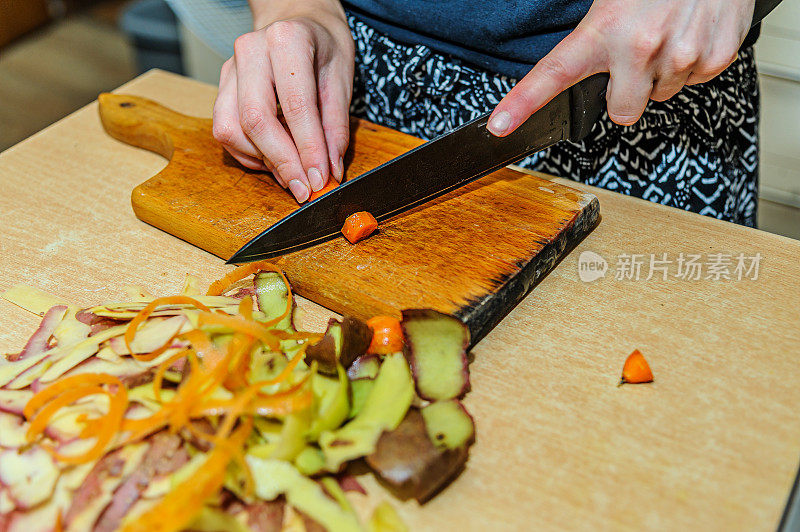 一个女人正在削胡萝卜，准备晚餐。