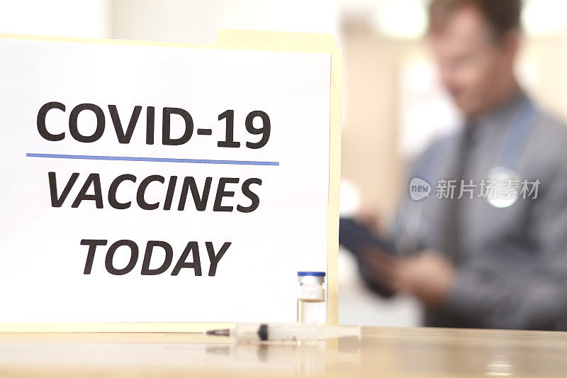 COVID-19:医生准备接种疫苗。标志，注射器，小瓶前景。